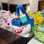 Arlington TX Birthday Bash Giveaway: A close-up of a blue shark-themed Easter basket, among other colorful baskets, prepared for the Seasons of Change Inc. community event on April 17th.